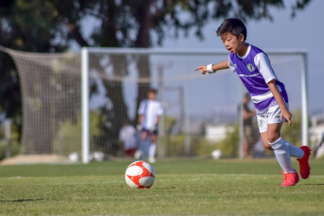 A child running up to a soccer ball during a game.